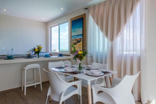 a dining room with a white table and white chairs at Casa Leo in Playa del Carmen