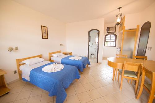 two beds in a room with a table and a dining room at Elite Hotel in Florianópolis