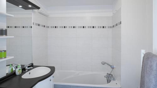 La salle de bains blanche est pourvue d'un lavabo et d'une baignoire. dans l'établissement Le Marengo: Charmant, Rénové, Terrasse, Parking privé, à Toulouse