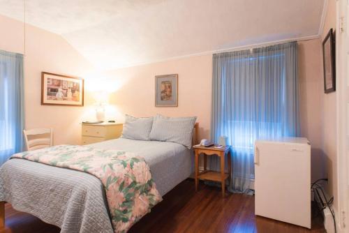 a hotel room with a bed and a desk and window at The Coolidge Corner Guest House: A Brookline Bed and Breakfast in Brookline