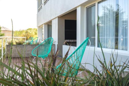two green chairs sitting on the patio of a house at Valeria Playa Apart in Valeria del Mar