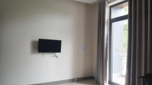 Une télévision à écran plat est installée sur un mur à côté d'une fenêtre. dans l'établissement Motel Thanh Long, à Đà Nẵng