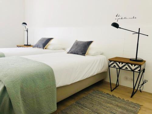 a bedroom with two beds and a lamp and a rug at Moderno apartamento, central e confortável in Montijo