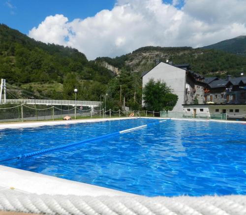 ein großer blauer Pool mit Bergen im Hintergrund in der Unterkunft Hotel Pradas Ordesa in Broto