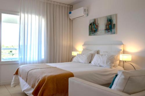 a bedroom with a large white bed and a window at Valeria Playa Apart in Valeria del Mar