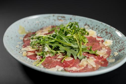a plate of food with meat and greens on it at Eden Hotel und Restaurant in Ilanz