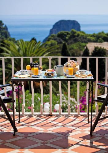 a table with food and orange juice on a balcony at Sina Flora in Capri