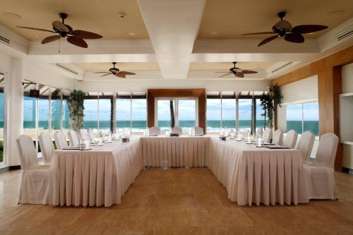 a room with long tables and white chairs and windows at Dusit Thani Laguna Phuket in Bang Tao Beach