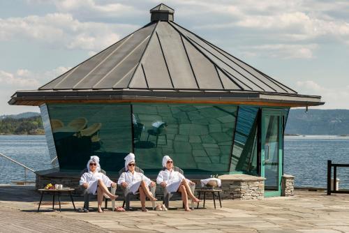 three women sitting in a gazebo on the water at Holmen Fjordhotell in Nesbru
