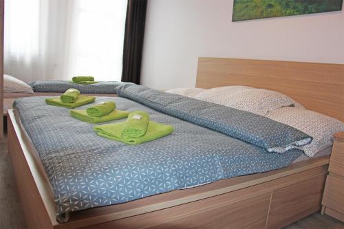 two green slippers are sitting on top of a bed at Ski apartman Klinovec in Loučná pod Klínovcem