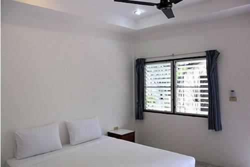 a bedroom with a white bed and a window at Hacienda Phuket, Patong in Patong Beach