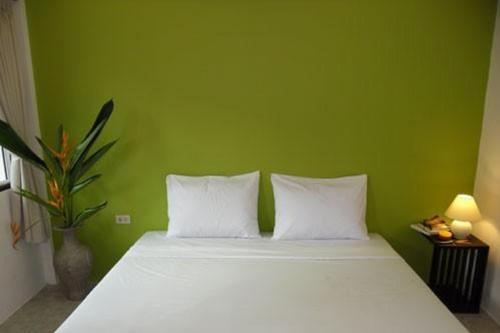 a green bedroom with a bed with two white pillows at Hacienda Phuket, Patong in Patong Beach