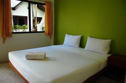 a bedroom with a white bed with a green wall at Hacienda Phuket in Patong Beach