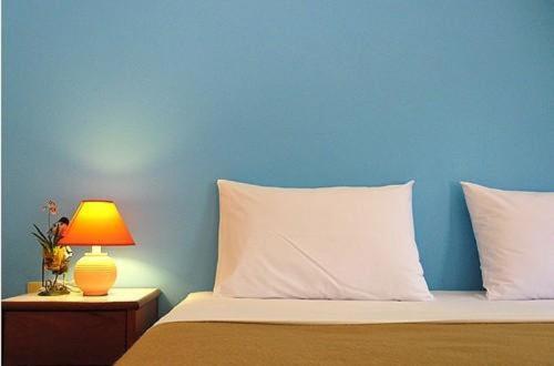 a bed with a blue wall and a table with a lamp at Hacienda Phuket, Patong in Patong Beach