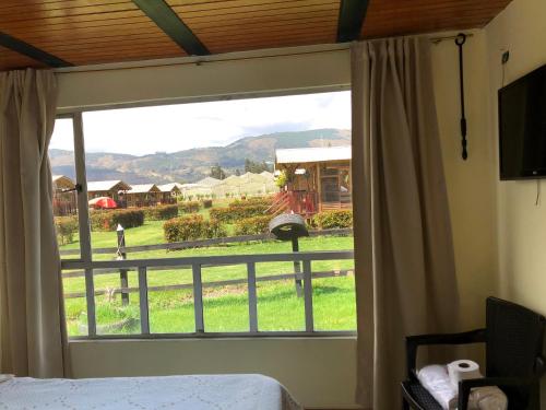 a bedroom with a window with a view of a field at CABAÑAS VILLA INES DE SUESCA in Suesca