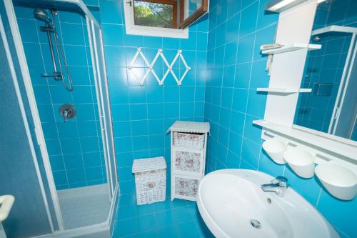 a blue tiled bathroom with a sink and a shower at Condominio Dunelba in Marina di Campo
