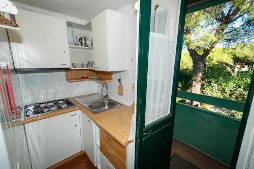 a small kitchen with white cabinets and a window at Condominio Dunelba in Marina di Campo