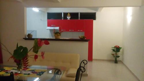 a living room with a table and a red kitchen at CHEZ MIMI in Gros-Morne