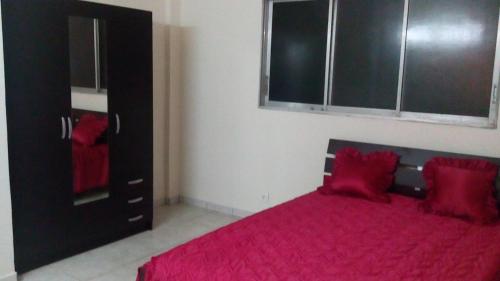 a bedroom with a red bed and a black cabinet at CHEZ MIMI in Gros-Morne