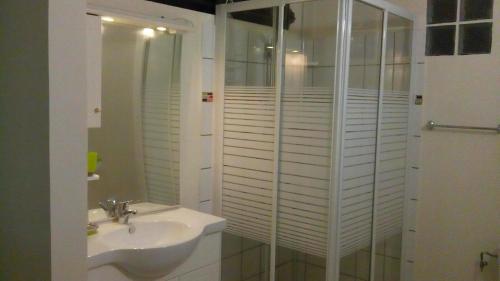 La salle de bains blanche est pourvue d'un lavabo et d'une douche. dans l'établissement CHEZ MIMI, à Gros-Morne