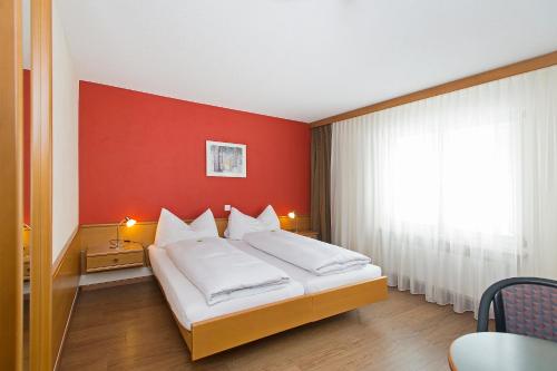 um quarto com uma cama com uma parede vermelha em Hotel Sportcenter Fünf Dörfer AG em Zizers