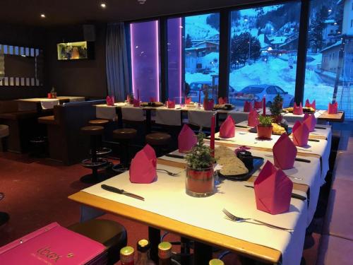 a row of tables in a restaurant with pink chairs at Ibex Hostel in Nauders