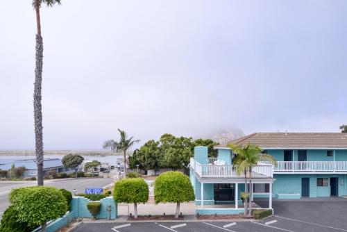 a blue building with palm trees in a parking lot at Bay View Inn - Morro Bay in Morro Bay