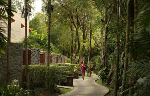 a woman walking down a path in a park at Dusit Thani Laguna Phuket in Bang Tao Beach