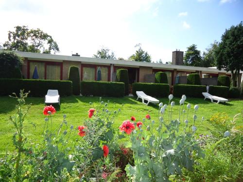 een tuin met rode bloemen en een gebouw bij Claes Compaen in Midsland