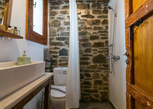 a bathroom with a toilet and a stone wall at Milos Dream Life in Triovasálos