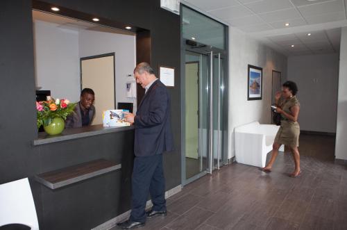 a man in a suit standing at a counter with a box at Adonis Paris Sud in Chevilly-Larue