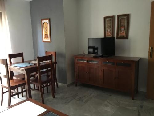 uma sala de estar com uma mesa e uma televisão e uma mesa e cadeiras em Apartamento céntrico em Ceuta
