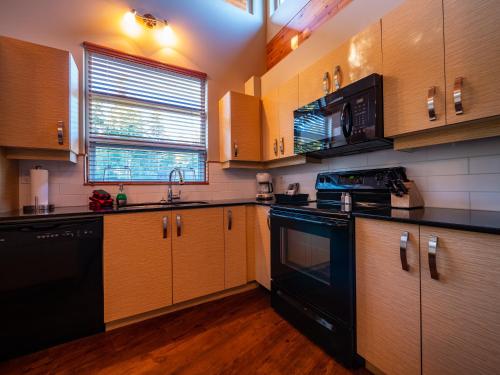 a kitchen with wooden cabinets and black appliances at The Cabins at Terrace Beach in Ucluelet