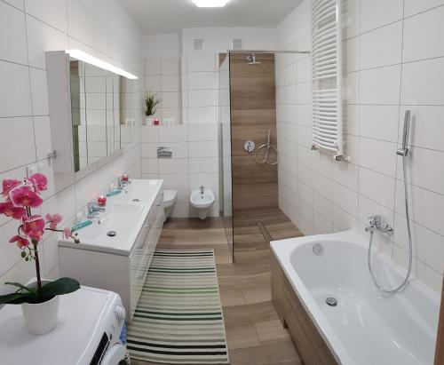 uma casa de banho com 2 lavatórios, uma banheira e um WC. em Apartamenty Elbląg em Elblag