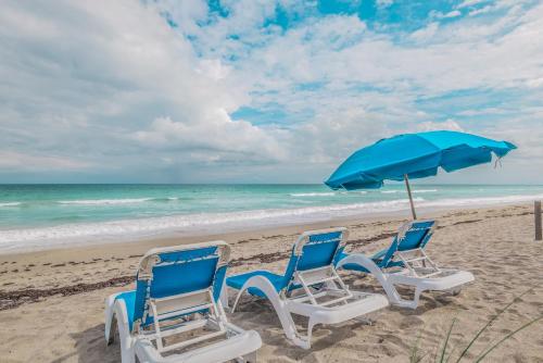 two chairs and an umbrella on a beach at Turtle Reef Club in Jensen Beach