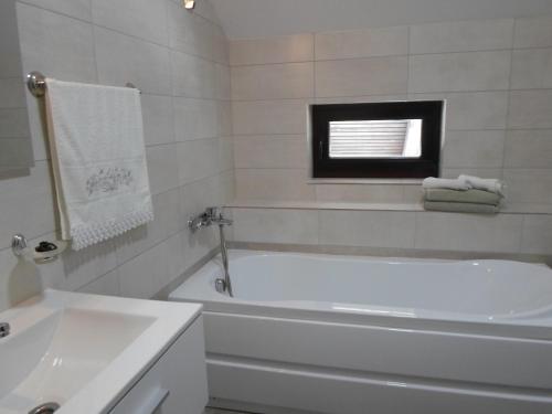 a white bathroom with a tub and a sink at Casuta din Gradina in Mănăstirea Humorului