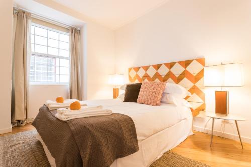 a bedroom with a white bed with a large window at Downtown - Chiado & Me in Lisbon