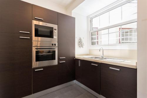 a kitchen with brown cabinets and a sink and a window at Downtown - Chiado & Me in Lisbon