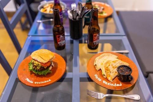 two plates of food and bottles of beer on a glass table at Mala Vecindad Beer Hotel in Mexico City