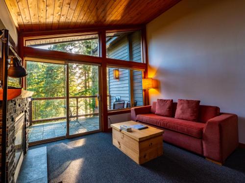 a living room with a red couch and large windows at The Cabins at Terrace Beach in Ucluelet