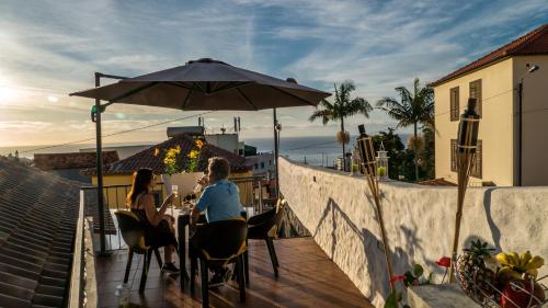 two people sitting at a table under an umbrella at Little Townhouse Funchal in Funchal