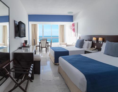 a hotel room with two beds and a table and chairs at Park Royal Beach Mazatlán in Mazatlán