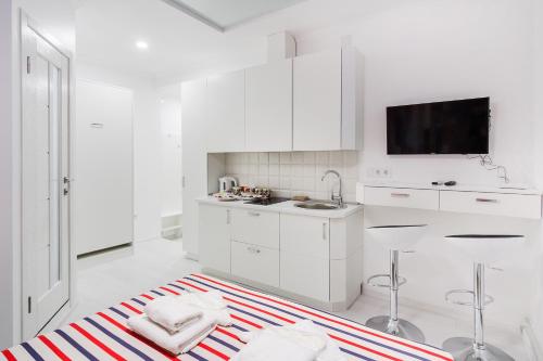 a white kitchen with white cabinets and a sink at Rose d'Opera Hotel in Odesa