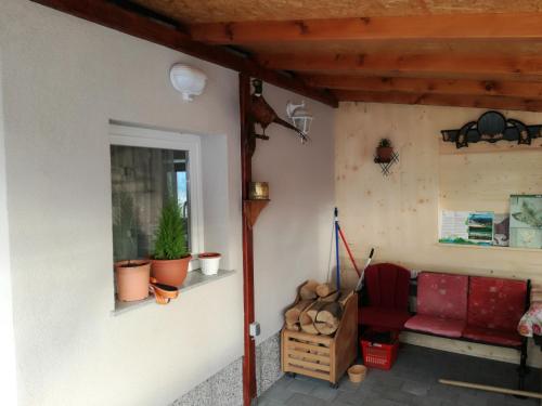 a porch with a red couch and a window at Kuća za odmor "Jasna" (Holiday home "Jasna") in Crni Lug
