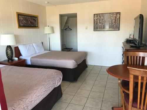 a hotel room with two beds and a table at Value Lodge Motel in Nanaimo