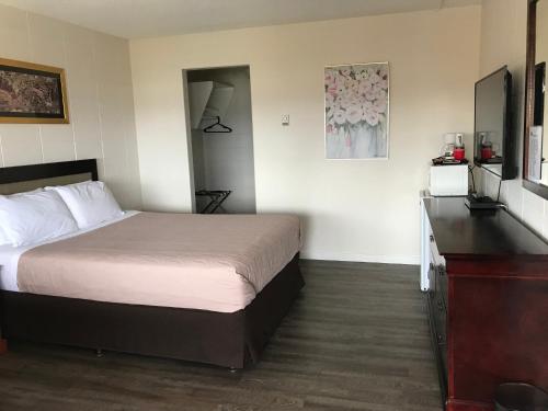 a hotel room with a bed and a dresser at Value Lodge Motel in Nanaimo