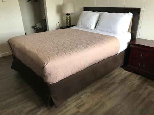 a large bed in a room with a wooden floor at Value Lodge Motel in Nanaimo
