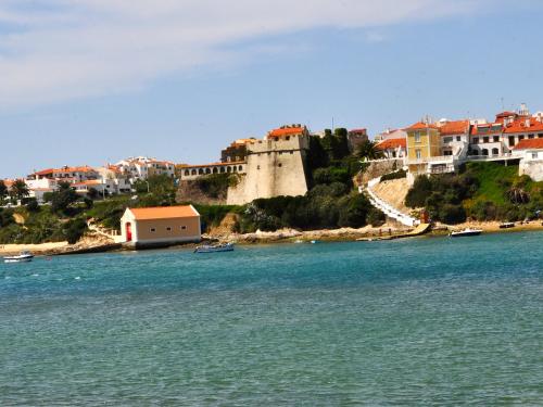 a group of boats in the water next to a castle at Apartamentos da Vila - Duna Parque Group in Vila Nova de Milfontes