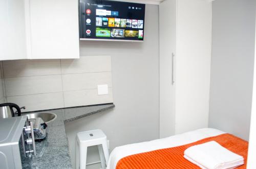 Habitación pequeña con cama y TV en la pared. en Cape Town Micro Apartments, en Ciudad del Cabo