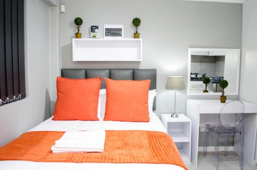 ein Schlafzimmer mit einem Bett mit orangefarbenen Kissen in der Unterkunft Cape Town Micro Apartments in Kapstadt